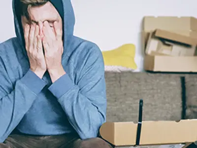 man sitting on couch holding his face