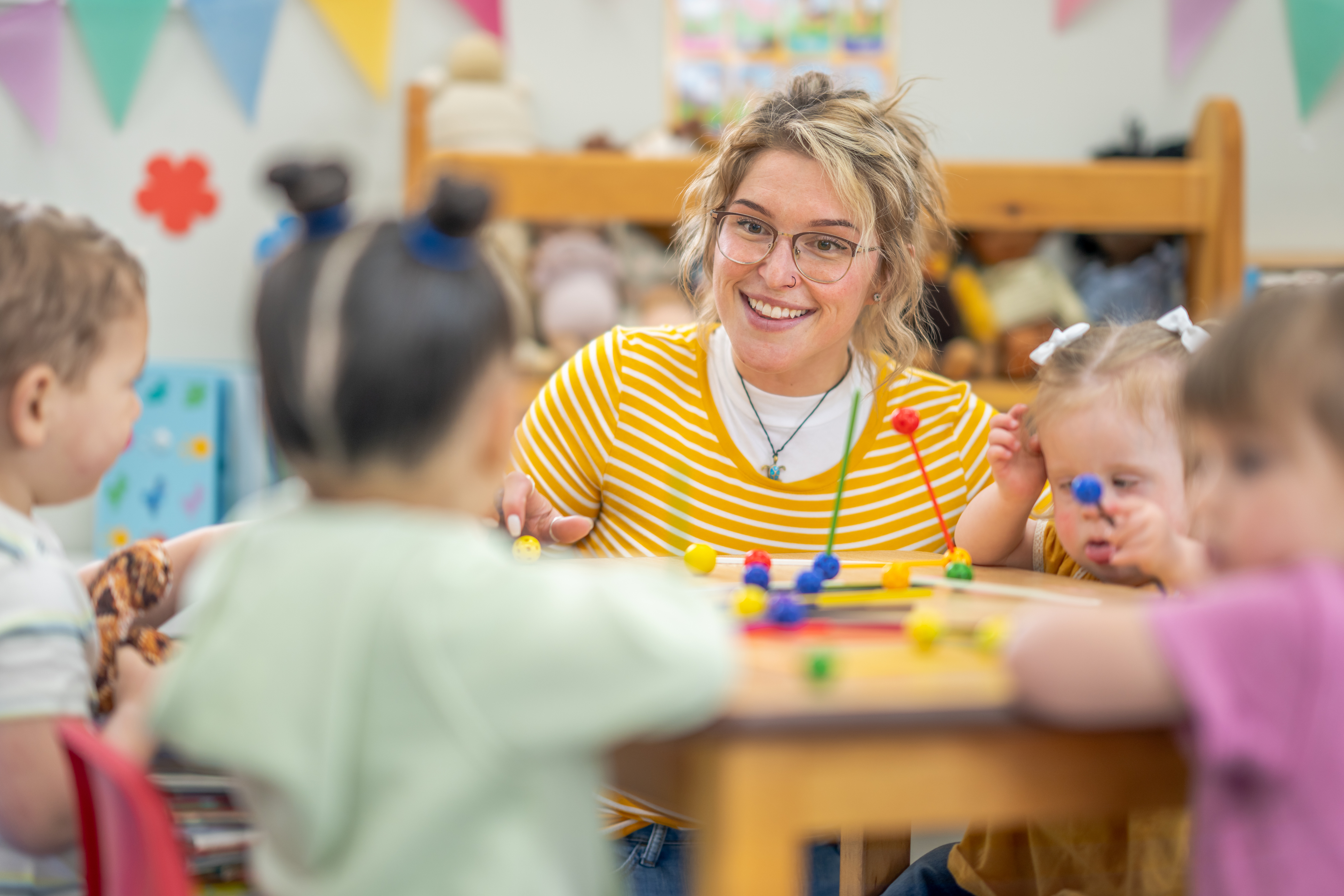 Educator playing with children at a table