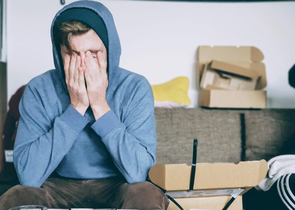 man sitting on couch with his hands on his face