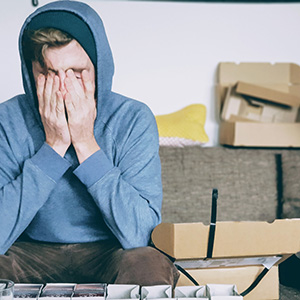 man sitting on couch holding his face