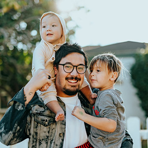 man holding two children and smiling