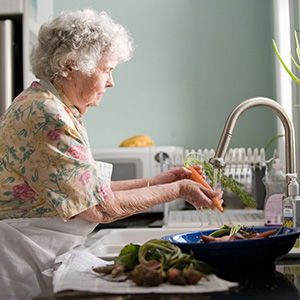senior woman washing vegetables in the sink