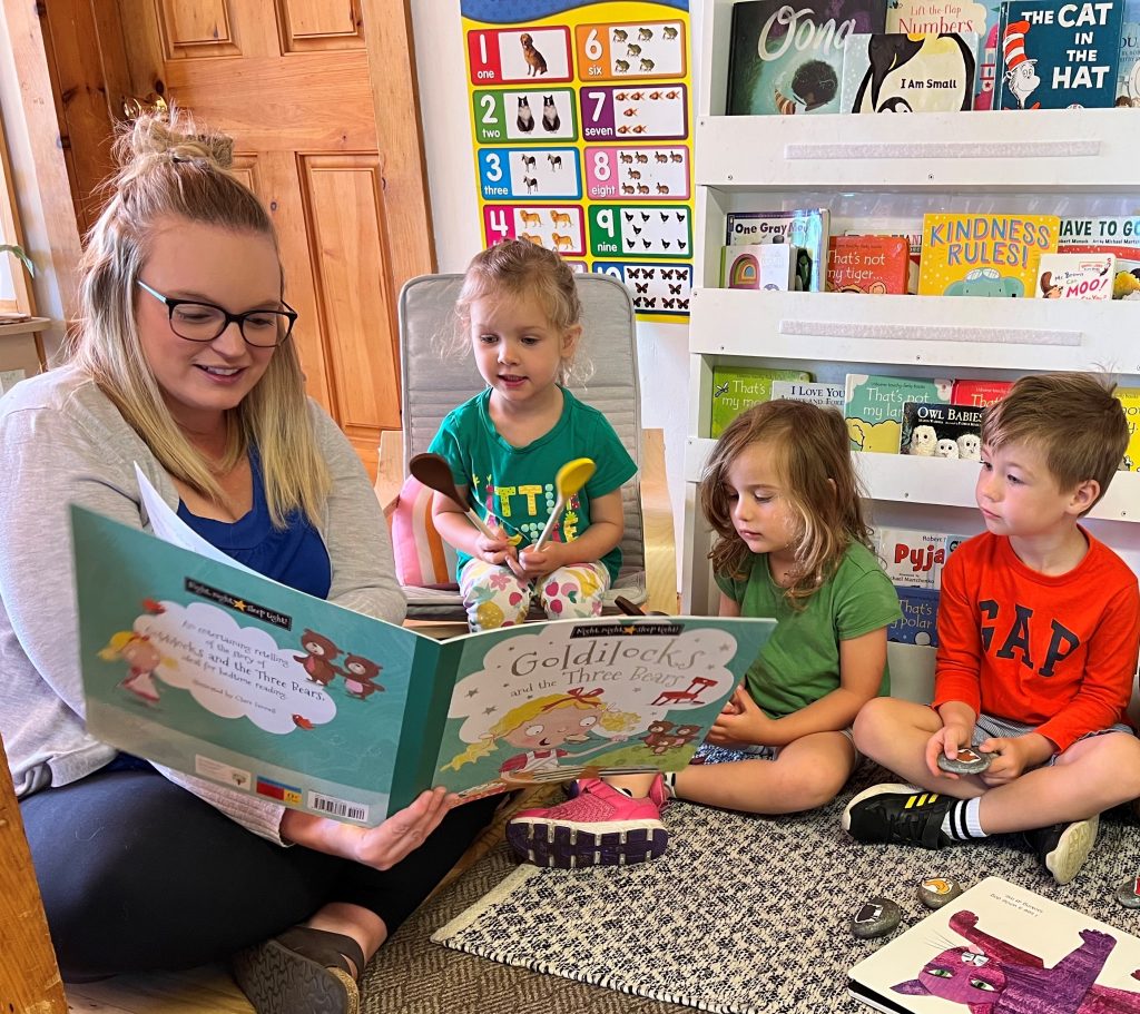 children sitting to hear a book read by an early childhood educator