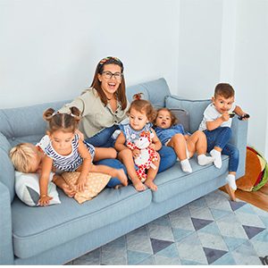 woman sitting on a blue couch with 5 young children
